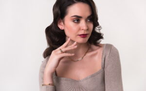 Tanara in tinuta smart casual, cu bluza cu decolteu, inel, bratara si lant de aur